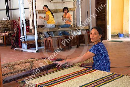 Vietnamese woman manufacturing woven rugs at a craft center in Hoi An, Vietnam.