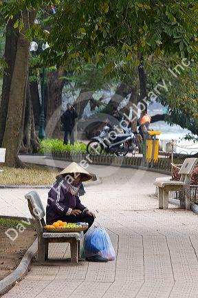 Vendor selling fruit on park benches along the Hoan Kiem Lake in Hanoi, Vietnam.