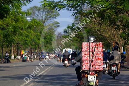 Vietnamese man transports cases of coca cola on the back of his motorbike on the National Highway 1 at Hue, Vietnam.