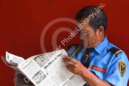 Vietnamese security guard reading a newspaper in Ho Chi Minh City, Vietnam.