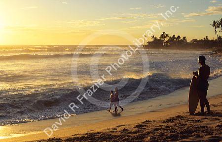 Surfer at sunset on Makaha Beach in Oahu, Hawaii.