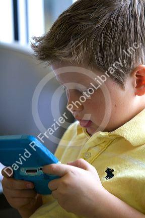 Boy playing with a personal video game system at the Boise Airport, Idaho, USA. MR