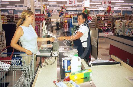 Woman paying for her groceries at the customer check out in a grocery store.