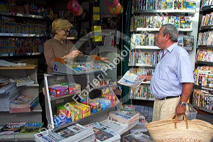 French man purchasing a newspaper from a Presse news kiosk in Sanary-sur-Mer, France.