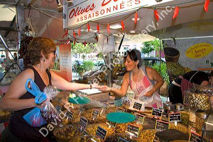 Customer purchasing produce from an outdoor market vendor in Sanary sur Mer, Southern France.