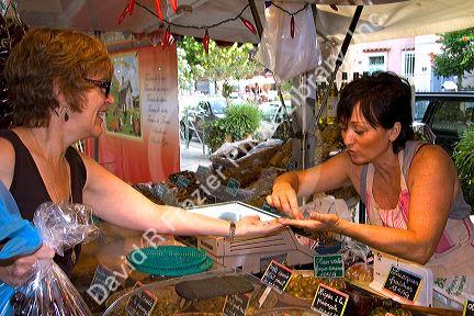 Customer purchasing produce from an outdoor market vendor in Sanary sur Mer, Southern France.