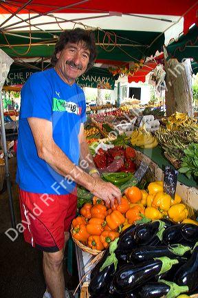 French vendor stocking produce at an outdoor market in Sanary sur Mer, Southern France.