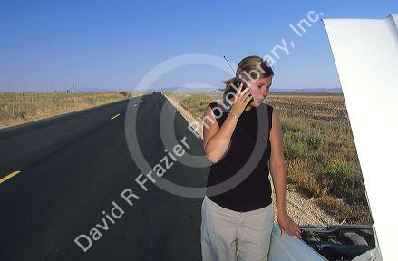 Stranded woman using a cell phone to call for help.