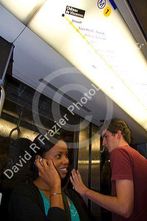 Passenger speaking on a cell phone while riding on the Paris Metro in Paris, France.