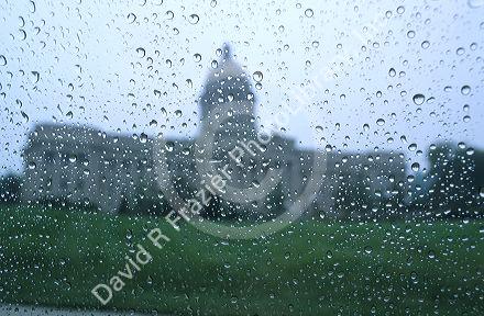 Rain drops on a window with the Kentucky state capitol building in the background.