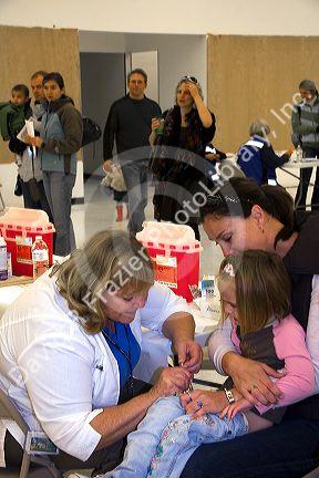 Health care professional administering an injection of the H1N1 influenza vaccine to a child in Boise, Idaho.