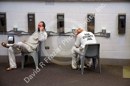 Inmates talk on telephones in the day use area of a county jail.