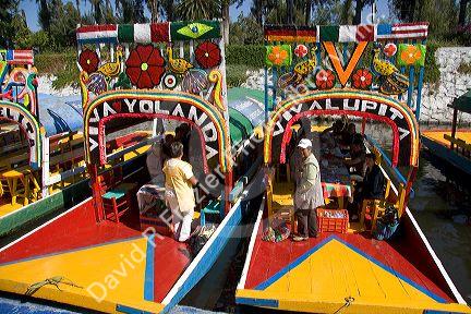 Colorful trajineras travel on the Xochimilco canals within Mexico City, Mexico.