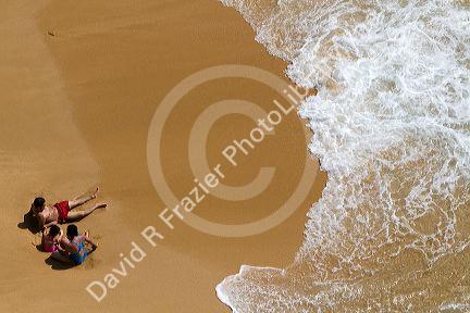 A family sits on the beach in the surf at Acapulco, Guerrero, Mexico.