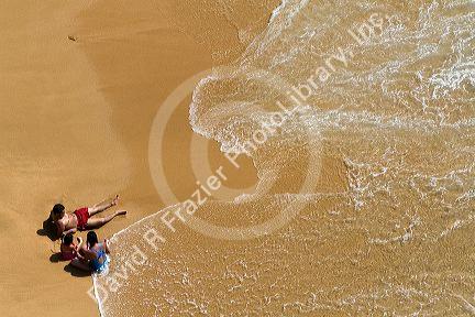 A family sits on the beach in the surf at Acapulco, Guerrero, Mexico.