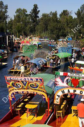 Colorful trajineras travel on the Xochimilco canals within Mexico City, Mexico.