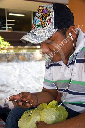 Mexican male student listening to an MP3 player on the campus of Universidad Autonoma de Guerro located in Acapulco, Guerrero, Mexico.