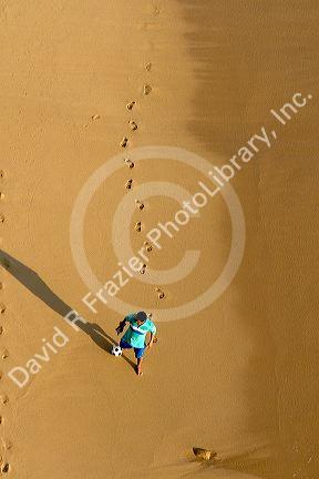 Person kicking a soccer ball on the beach at Acapulco, Guerrero, Mexico.