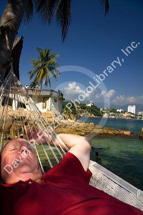 American tourist napping in a hammock on Island Roqueta, Acapulco, Guerrero, Mexico.