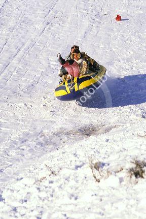 People sledding in the snow on an inflatable raft.