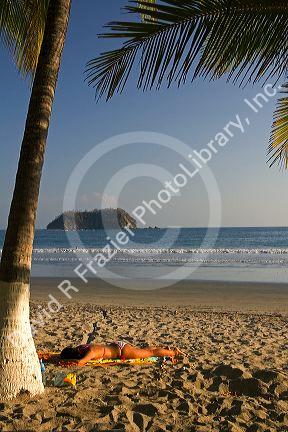 Woman sunbathing on the beach at Playa Samara, Costa Rica.