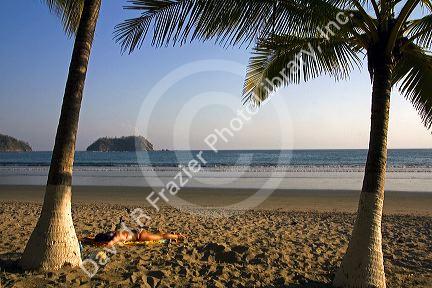 Woman sunbathing on the beach at Playa Samara, Costa Rica.