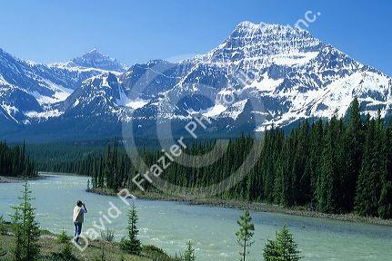 A woman takes a photograph of the Athabasca River and the Canadian Rockies in Jasper/Banff Park, Canada.