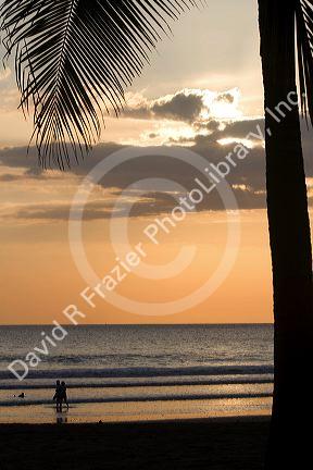 People walk on the beach at sunset in Jaco, Costa Rica.