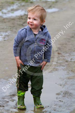 Young boy playing in mud puddles at Skagit Valley, Washington, USA.