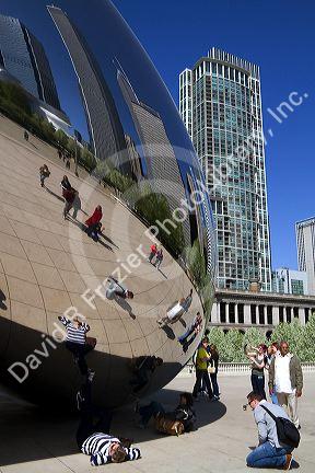 Visitors look at their reflection in the Cloud Gate public sculpture located at the AT&T Plaza in Millennium Park, Chicago, Illinois.