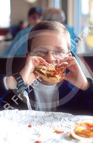 Young boy easting a cheeseburger.