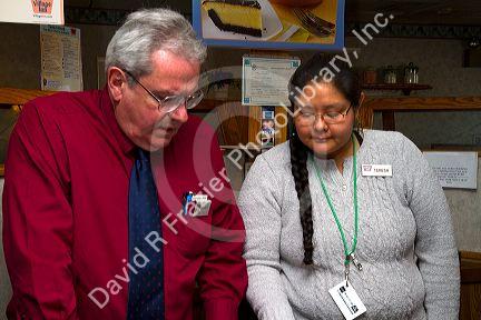 Navajo woman working as a restaurant hostess speaking with the manager in Farmington, New Mexico, USA.