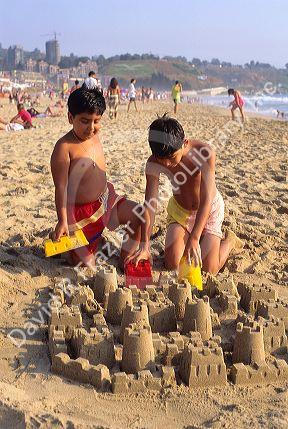 Young boys build a sandcastle on the beach in Renaca, Chile.