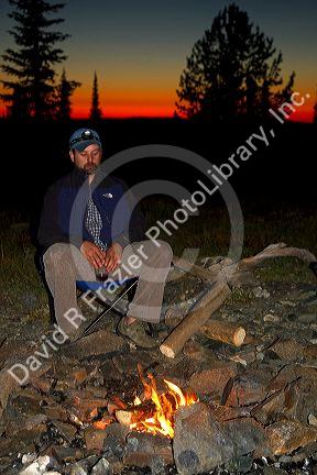 Man sitting by a camp fire at the summit of Green Mountain along the historic Magruder Corridor road that devides the Frannk Church-River of No Return Wilderness Area and the Selway-Bitterwoot Wilderness in Idaho, USA. MR