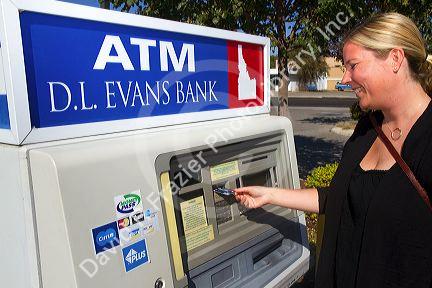 Woman making a cash withdrawal from and ATM in Boise, Idaho, USA. MR