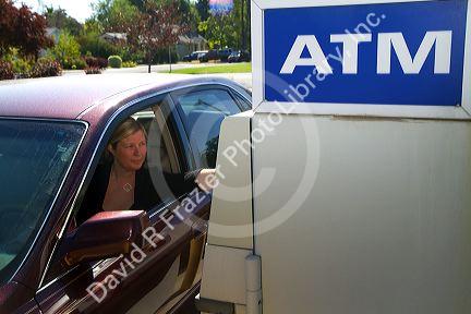 Woman making a cash withdrawal from and ATM in Boise, Idaho, USA. MR