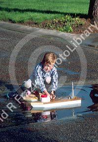 Six year old boy floating a home made model boat.  MR
