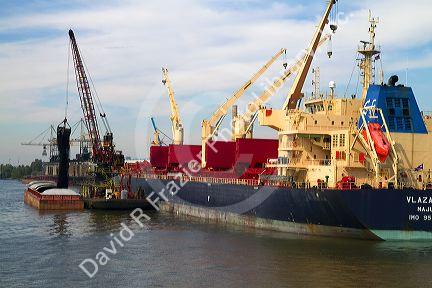 Crane loading a barge with coal on the Mississippi River at New Orleans, Louisiana, USA.