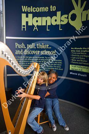 Child playing an electronic stringless harp at the Gulf Coast Exploreum Science Center in Mobile, Alabama, USA.