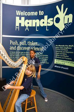 Child playing an electronic stringless harp at the Gulf Coast Exploreum Science Center in Mobile, Alabama, USA.
