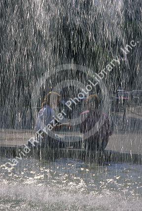 A couple sits behind a fountain in Frankfurt, Germany.