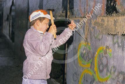 A young boy chipping off a piece of the Berlin Wall, Germany.