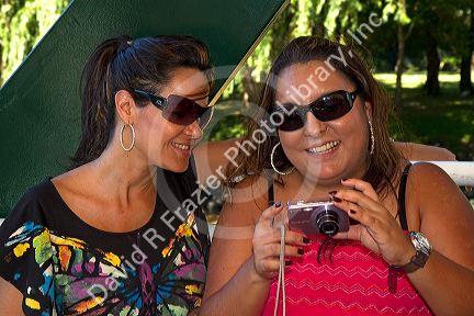 Women look at images on a digital camera at Tigre, Argentina.