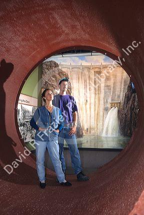 A couple stands inside a portion of syphon pipeline at Four Rivers Cultural Center in Ontario, Oregon.  The pipe provides irrigation water from Owyhee Reservoir depicted in background.