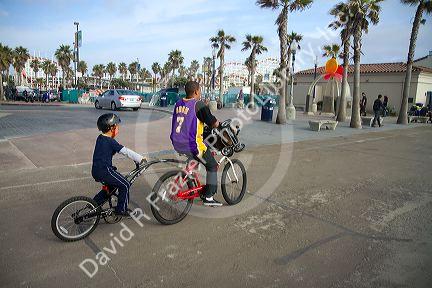 Kids ride bicycles at Mission Beach, San Diego, California, USA.