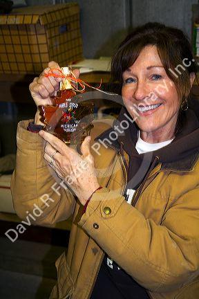Worker labeling bottles of maple syrup in a sugar shack at Lake Odessa, Michigan, USA.