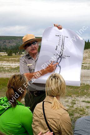 Park ranger giving a tour group information about Old Faithful geyser in Yellowstone National Park, Wyoming, USA.