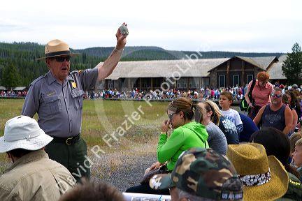 Park ranger giving a tour group information about Old Faithful geyser in Yellowstone National Park, Wyoming, USA.