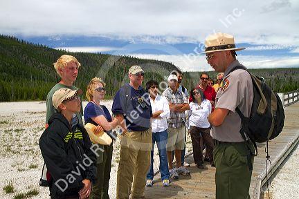 Park ranger giving a tour group information about the Upper Geyser Basin in Yellowstone National Park, Wyoming, USA.