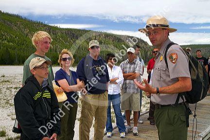 Park ranger giving a tour group information about the Upper Geyser Basin in Yellowstone National Park, Wyoming, USA.